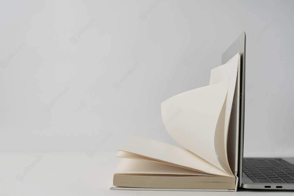 Полуоткрытая книга и ноутбук на столе